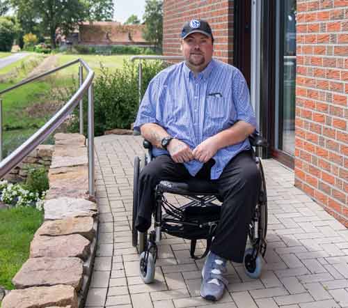 Oliver Otto, Versicherter der BG BAU, im Rollstuhl vor seinem Haus.