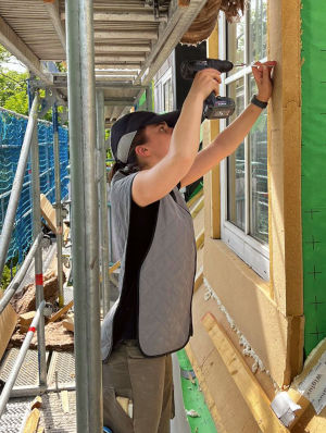Bauarbeiterin auf einer Baustelle an einem sonnigen Tag. Sie trägt eine Kühlweste und ein Kühl-Cap.