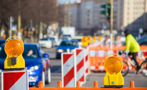 Straßenverkehr mit Autos und Radfahrer an einer Kreuzung mit Baustelle.