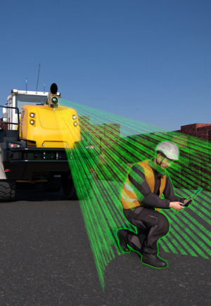 Eine Kamera ist an einem Baufahrzeug angebracht und erkennt einen hockenden Bauarbeiter vor dem Fahrzeug.