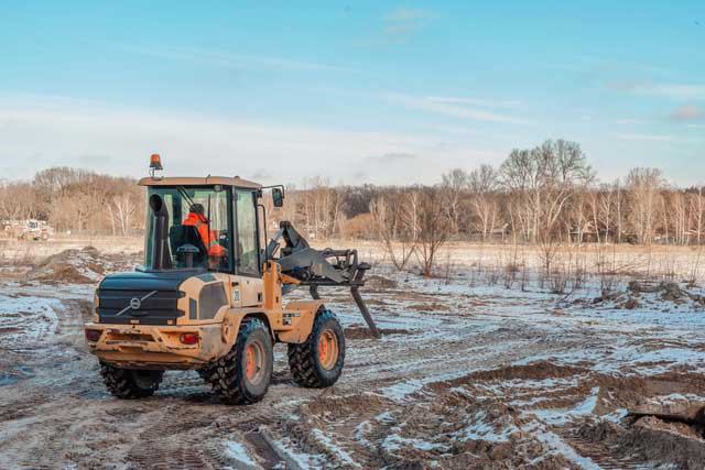 Ein Bagger fährt im Winter auf einer Baustelle.