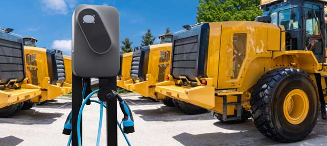 Mehrere Radlader stehen um eine Ladesäule herum.