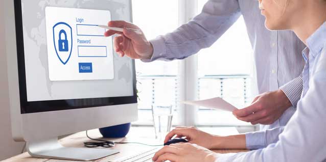 Zwei Personen schauen auf einen Computer-Bildschirm, wo eine Seite zu einem sicheren Loginbereich zu sehen ist.