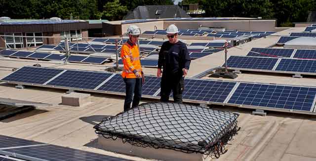 Eine Aufsichtsperson und ein Beschäftigter sprechen über die gesicherte Lichtkuppel auf einem Dach.  