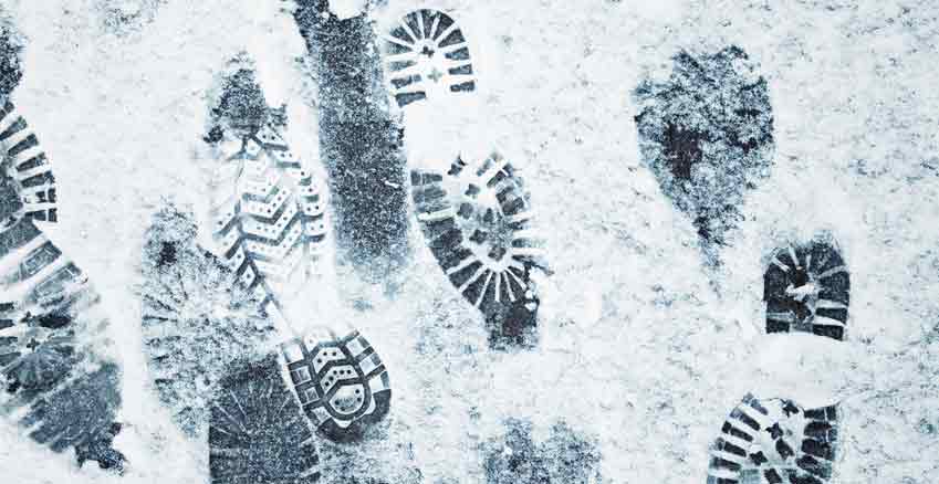 Auf einem Boden sind verschiedene Fußabdrücke im Schnee.